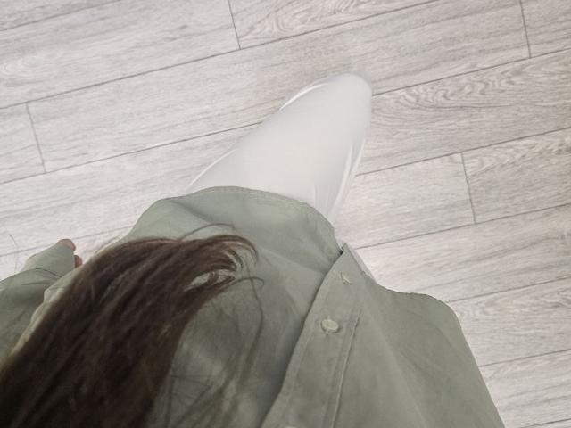 JuttaHillwig's white boot is in the foreground, with her green shirt and brown hair in the background, standing on light wood flooring. Her hand is slightly visible.