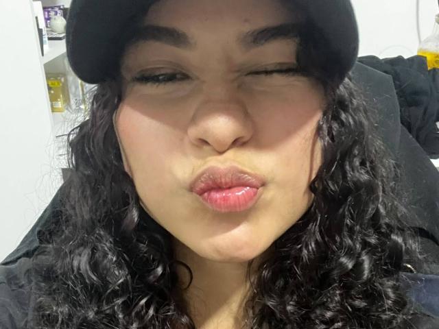 HemMastar with wavy black hair, black beret, and puffy pink lips making a pouty face, eyes half-closed, wearing a black jacket, in a selfie.