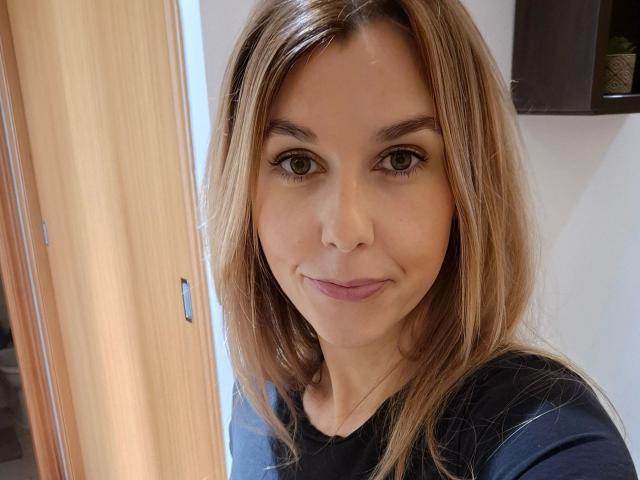 PekiPassionX-hot with medium brown hair, green eyes, and a slight smile, wearing a dark blue shirt, has a cute face and a small nose. PekiPassionX-hot's tits are small.