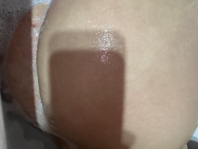 Luucie's wet, tan-lined ass with a dark brown, rectangular tattoo shadow. Her skin is glistening from soap bubbles. The image focuses on her right buttock and lower back.