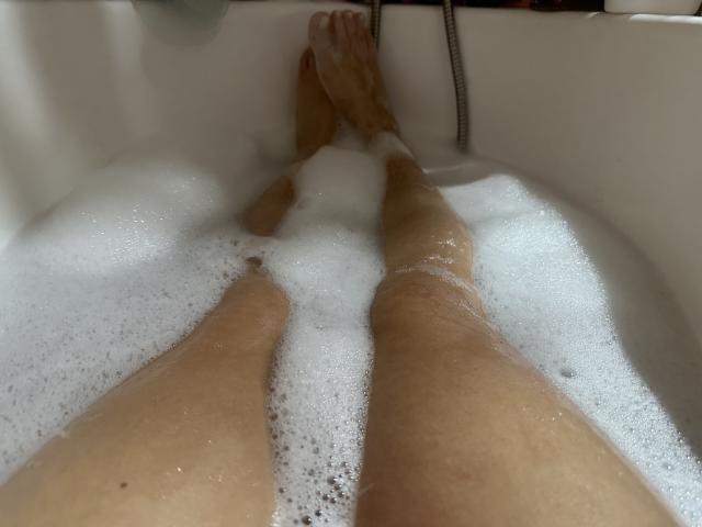 Luucie's legs in a bathtub, covered in white bubble foam, with toes at the top and her pussy slightly visible beneath the bubbles.