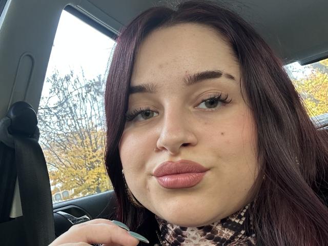 Luucie's face, medium skin tone, dark red hair, full pink lips, slightly upturned, green eyes, wearing a leopard print scarf, sitting in a car with a seatbelt.