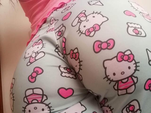 SofiaAnal's ass in tight, light-gray, Hello Kitty-patterned pants with pink hearts and bows, wearing a pink top, showing her curvy butt and snug, shiny fabric.