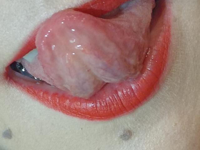 La lingua di OrianaLaFrancaise è nella sua bocca, umida e rosa, con le sue labbra rosse leggermente dischiuse. La sua lingua è spessa e con una consistenza particolare. Le sue labbra sono lucide e rosse..