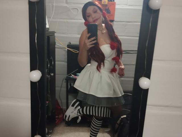 NatashaYou69 in a white strapless dress with red pom-poms, striped thigh-highs, and white sneakers, taking a mirror selfie with her phone, showing her tits and ass.