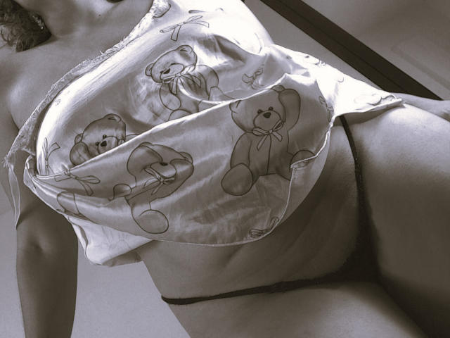 AmberDemons has a fluffy teddy bear print top, partially covering her big tits, and wears black panties, showing her curvy ass and smooth, pale skin. Monochrome.
