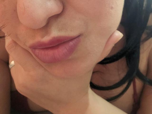 VivianaThompson's pink pout is slightly parted with her hand gently touching her cheek, black hair cascading, fair skin, and a subtle nose, close-up shot.