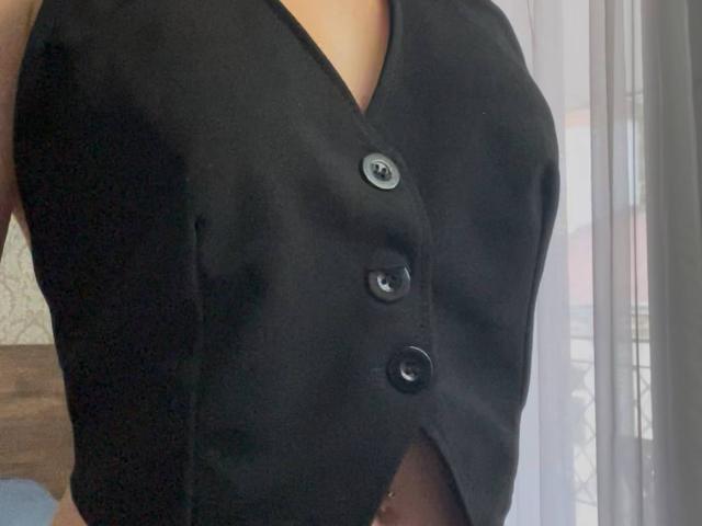 AlexXas in a black button-up vest, showing her tits, with three buttons and a slight cutout. Her upper body is visible, arms out of frame.
