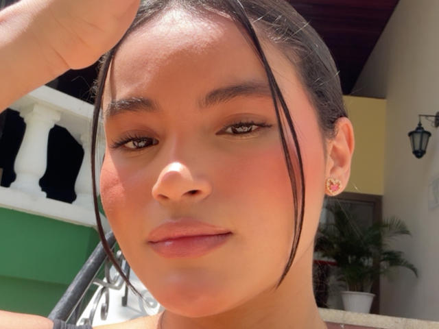 MiiaPalmer has a cute face with brown eyes, straight black hair, and pink earrings. She's holding her hair up, showing off her slightly flushed, glossy lips.