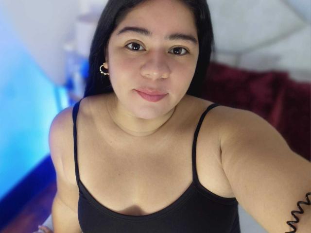 ElizaWiliamst tem olhos castanhos, cabelo preto e veste uma blusa preta com alças finas. Seus seios pequenos e rosto redondo são visíveis. Ela tem um piercing no nariz e uma tatuagem em espiral..