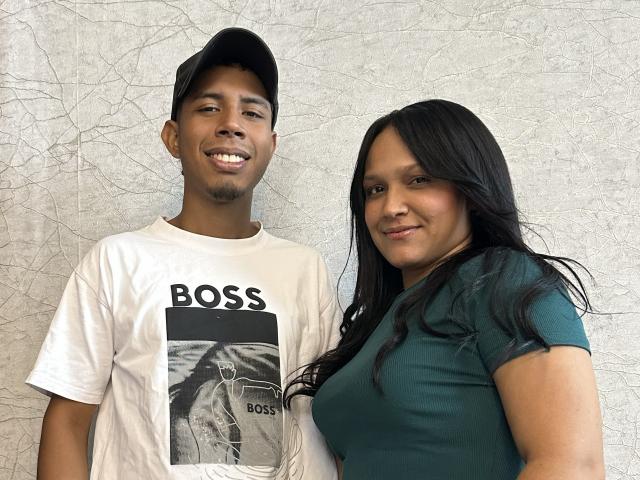 SofiaAndAndres with dark skin, black cap, white shirt, and BoSS graphic, standing next to SofiaAndAndres with dark skin, long black hair, green shirt, and slight smile.