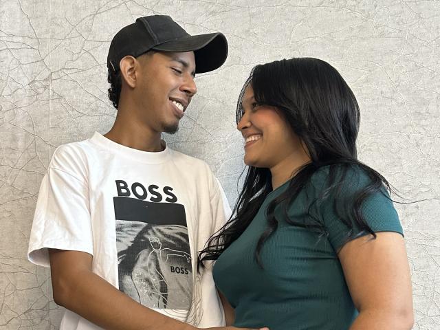 SofiaAndAndres with dark skin, smiling, wearing a green tee and black hair, stands next to Andres with light brown skin, a baseball cap, and white "BOSS" tee.