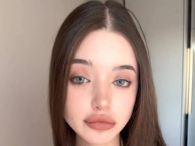 CatinaLetchworth has light blue eyes, straight brown hair, and full, pinkish-brown lips. Her skin is fair and she's looking straight at the camera with a neutral expression.