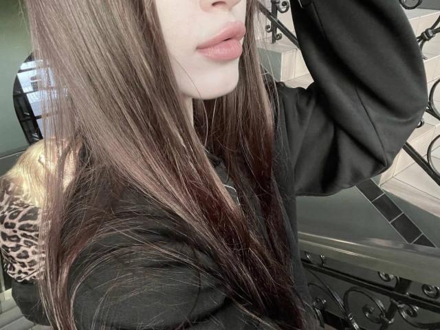 CatinaLetchworth with long brown hair, black shirt, leopard print sleeve, arm raised, pouty pink lips, pale skin, partial face visible, indoors, soft light, elegant, subtle makeup.