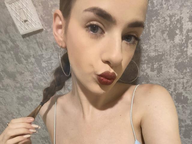 MarcelleMantz has pouty lips, small tits, and is making a puckering face. She's wearing hoop earrings and a thin-strapped top, with a braid over her shoulder.