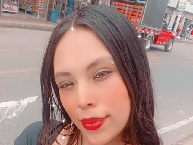 ValentinaRicci has long black hair, red lipstick, and metal eyebrow studs. She's smiling with her eyes slightly closed. Her nose is small and her skin is light.