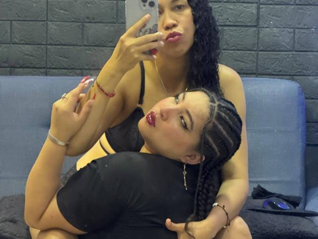 CharlotteTiffany with curly hair, black bra, and red lipstick, kissing mirror selfie of CharlotteTiffany with braided hair, black shirt, and red lipstick, holding phone.