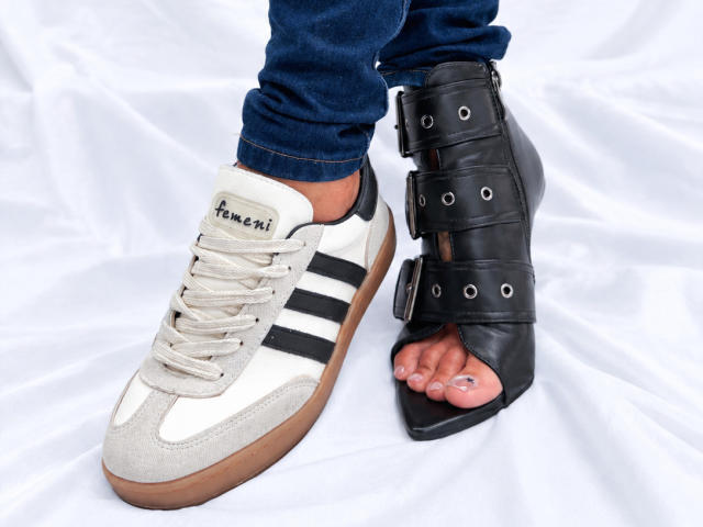 LailaCastillo's feet show a white and black Adidas sneaker on one foot and a black, strapped, open-toe shoe covering the other. Her blue jeans are slightly pulled down.