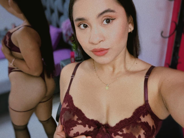HannaHarper with medium brown skin, black hair, and red lipstick, wearing maroon lace lingerie, showing her tits and ass in a mirror selfie, gold necklace, and black stockings.