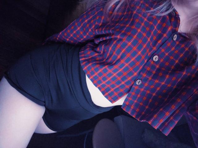 TiffaniMacandog's plaid shirt, red and blue, buttoned, with black shorts, showing a sliver of white skin, and her thigh. Her purple hair is partially visible.