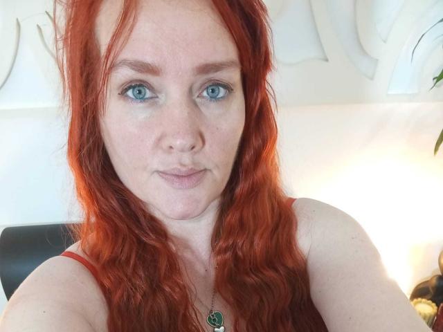 SinFulTitsDD ha i capelli rossi e ondulati, gli occhi azzurri e un leggero sorriso. Indossa una maglietta rossa con una collana verde. La sua pelle chiara è cosparsa di lentiggini..