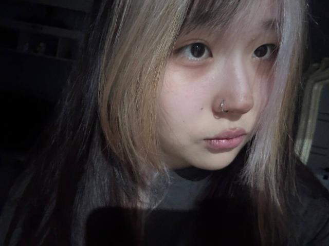 JungMcgranor has pale skin, small nose ring, and light brown hair with blonde highlights, looking serious with slightly parted pinkish lips. She has a small, cute ass.