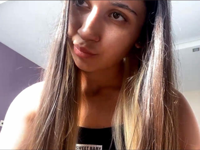 Brenda Bovia, con lunghi capelli castani lisci, pelle color nocciola e un sorriso discreto, indossa una canotta nera che mette in mostra le spalle e il décolleté..