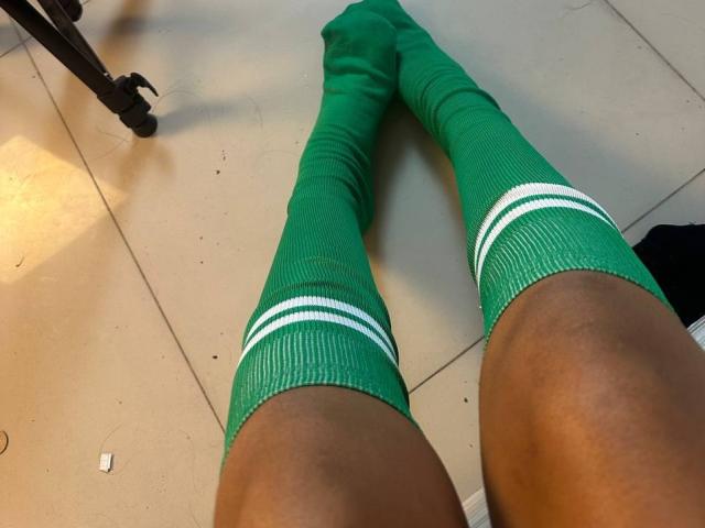 PaulineRey's green knee socks with white stripes, stretched out on a tiled floor, showing her dark brown thighs. The socks cover her lower legs.
