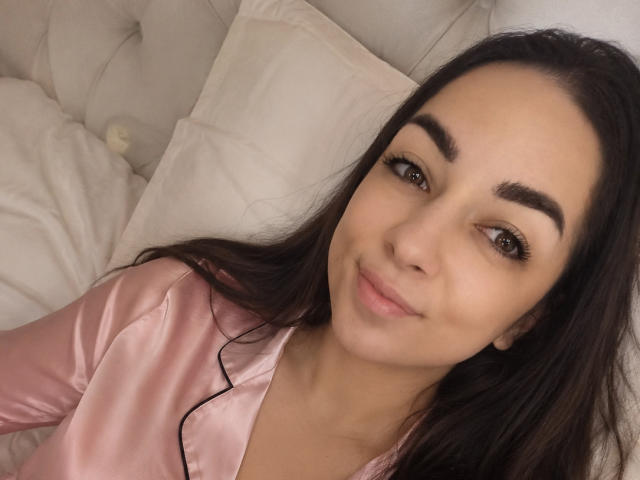 PolinkaN a les yeux marron, de longs cheveux noirs et un teint clair. Elle porte une chemise rose en satin et regarde l'appareil photo avec un léger sourire. Ses seins sont petits..