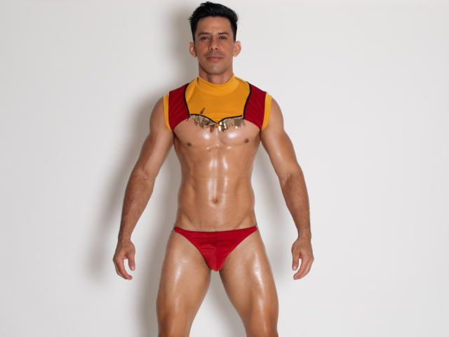 JoseRumBerotop, muscular, tan-skinned, short black hair, mustache, shiny skin, red and yellow sleeveless top, red Speedo, standing, arms down, looking at camera, chest exposed, semi-erect.