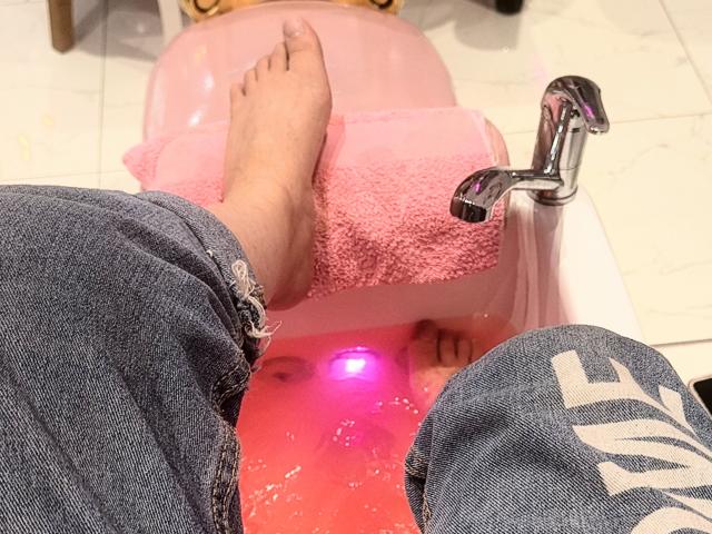 StephanieSun's bare ass is in a pink plastic baby bathtub with a towel, her feet are in blue jeans, and a shiny faucet is on the right.