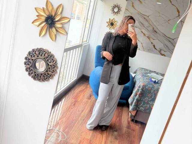 ElenaSaenz stands in front of a mirror, taking a selfie. She's wearing a black top, grey pants, and a black jacket, with medium tits and a slim build.