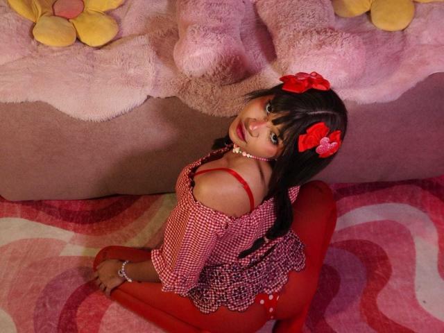 LiMiuu has dark hair with red bows, wearing a red checkered top, red tights, and red stockings. She's kneeling, showing her back, with a pearl necklace.