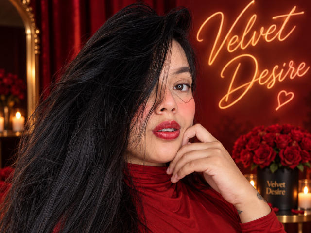 ViolettaRouse with long black hair, red lipstick, and red dress, touching her chin with her right hand, looking at the camera, background has red roses and neon text.