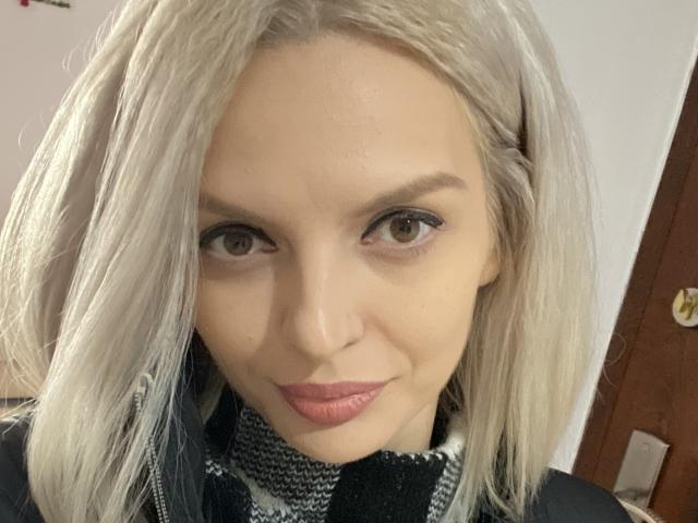 DouceAmelia tiene cabello rubio, piel clara, ojos marrones y lápiz labial rosa. Lleva un pañuelo a cuadros negros y blancos. Su rostro tiene una ligera sonrisa..