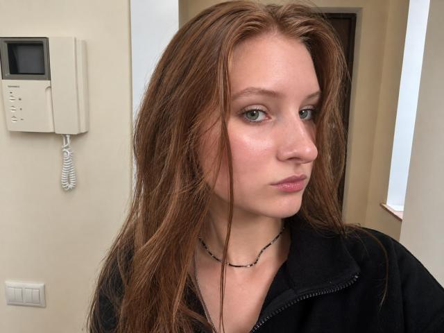 ArdelleCooksey has long, wet brown hair, light green eyes, and a serious expression. She's wearing a black zip-up hoodie and a thin black necklace.