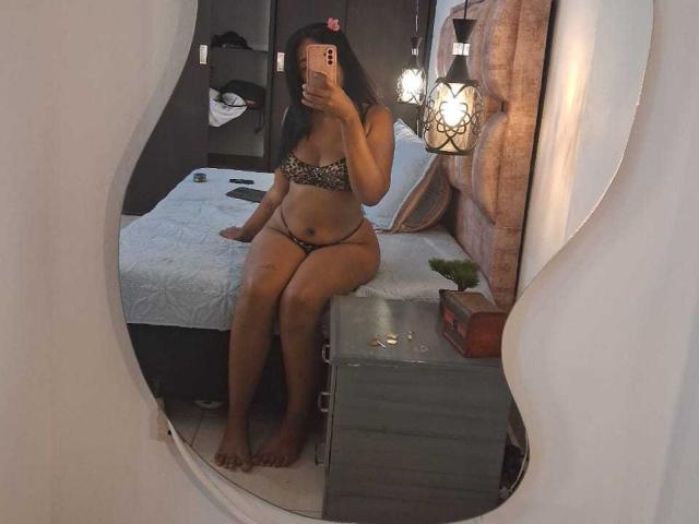 MiaStClaire in leopard-print lingerie, sitting on a bed, holding a phone, showing her tits and pussy in a mirror reflection. Her ass is slightly visible, too.