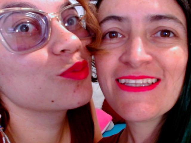 LunaVenus with glasses, red lipstick, and freckles, pouting. LunaVenus with black hair, red lipstick, and smiling. Both have fair skin and are in a selfie.