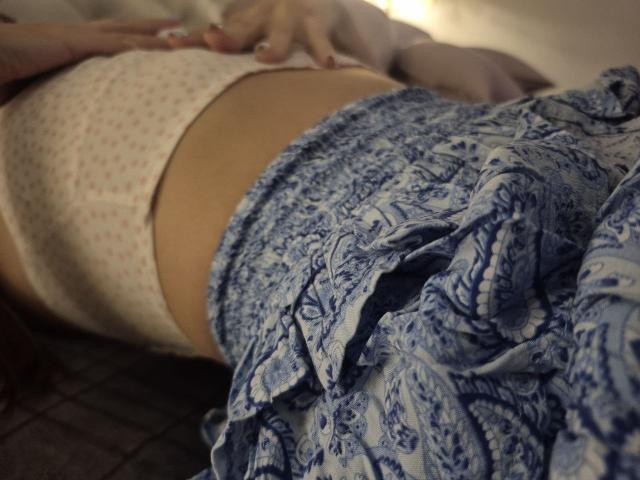 TenerliRize's white panties with tiny red dots, and a blue paisley skirt are visible. Her hands rest on her midriff, showing her bare stomach.