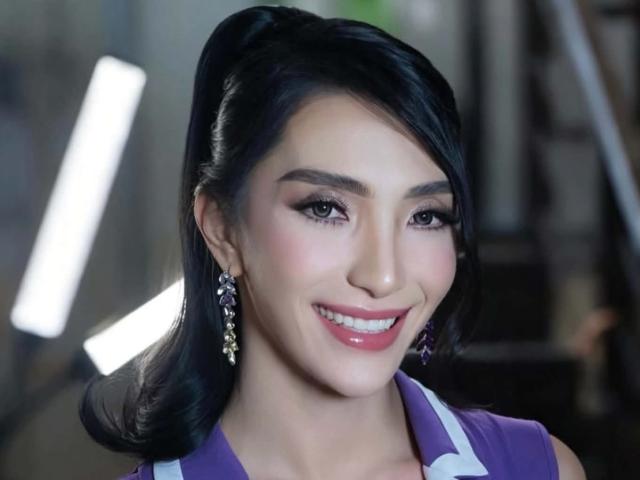 SexyLovelinessX with dark hair in a side pony, wearing purple earrings, smiling with pink lipstick, purple and white top, and purple eyes. Blush highlights her cute face.