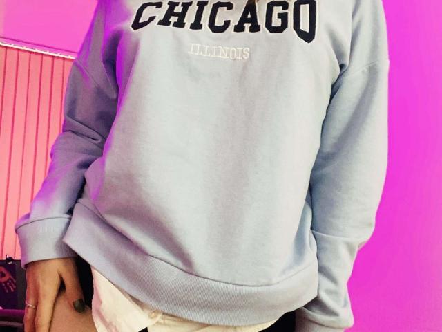 KarKutie wearing a light blue Chicago sweatshirt with long sleeves, showing their white underwear, and a pink-lit background, focusing on their torso and slightly raised butt.