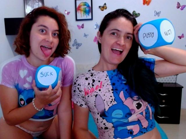 LunaVenus with curly brown hair and pink heart shirt, holding blue cup labeled "SUCK," sticking tongue out. LunaVenus with black hair, blue and pink "Stitch" shirt, holding "DICK" cup.
