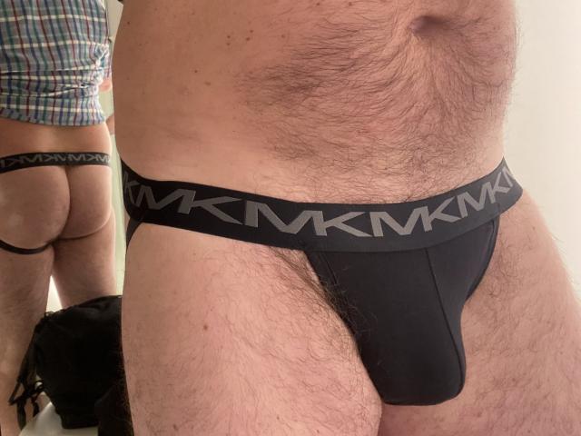 OfficeBitcyh's hairy belly and black V-Knicks, showing a bulge in the front, with a butt in the mirror wearing similar V-Knicks, showing a thong outline.