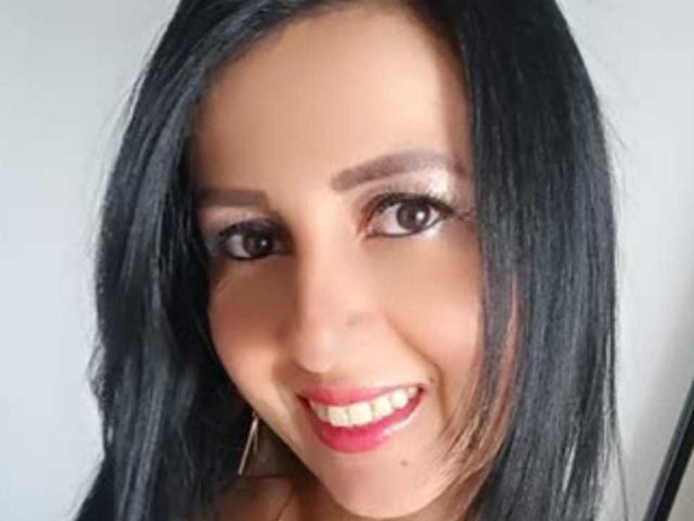 AgathaBrunner's face with straight black hair, brown eyes, red lipstick, and a smile, wearing hoop earrings. She has a tan complexion and a cute, sexy look.