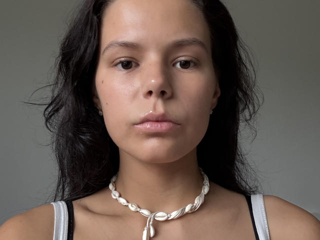 ClarenceGarin heeft een lichtbruine huid, donker golvend haar, kleine donkere ogen en een neutrale uitdrukking. Ze draagt een witte ketting van schelpen en een wit tanktop..