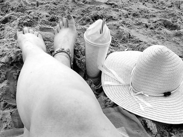 HotSandy4You-sex's legs on sandy beach, wearing a bracelet, with painted toenails, ice cream cone, and a wide-brimmed hat. Ass and legs are visible, feet up.