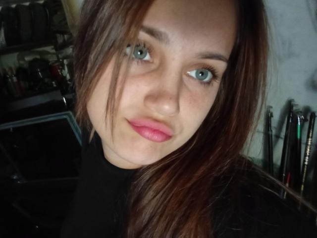 Georgina Brockwell ha gli occhi azzurri, le labbra rosa e i capelli castani, e indossa un maglione nero a collo alto. Il suo viso è leggermente inclinato, con un sorriso appena accennato. Il suo seno non è visibile..