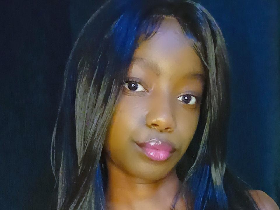 Zaeell69 has dark brown skin, long black straight hair, brown eyes, and pink glossy lips. She's looking slightly to the side with a neutral expression.