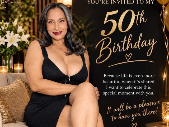 BilexyMature is a curvy woman with large boobs, wearing a black dress, sitting with crossed legs, smiling at the camera. She has gray hair and is on a couch.