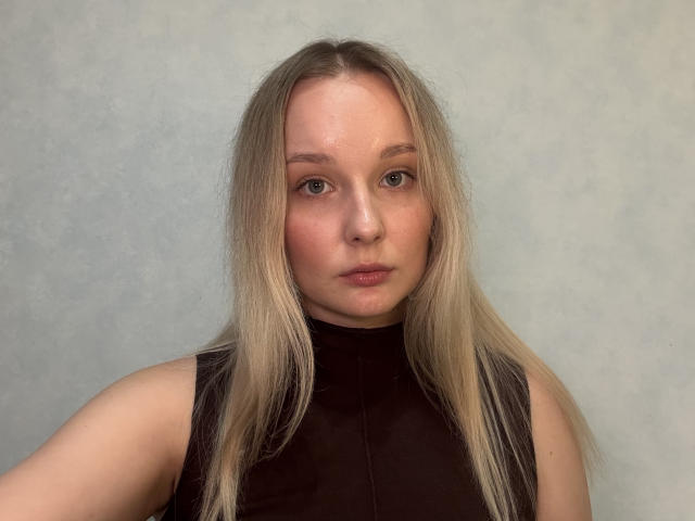 Leonarda Niziol, avec ses cheveux blonds, sa peau claire et ses lèvres roses, portant un haut noir sans manches, regarde directement l'appareil photo avec une expression neutre..